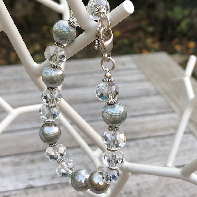 Bracelet composé de perles facettées en cristal et de perles en métal argenté. Fermoir et breloques en argent.