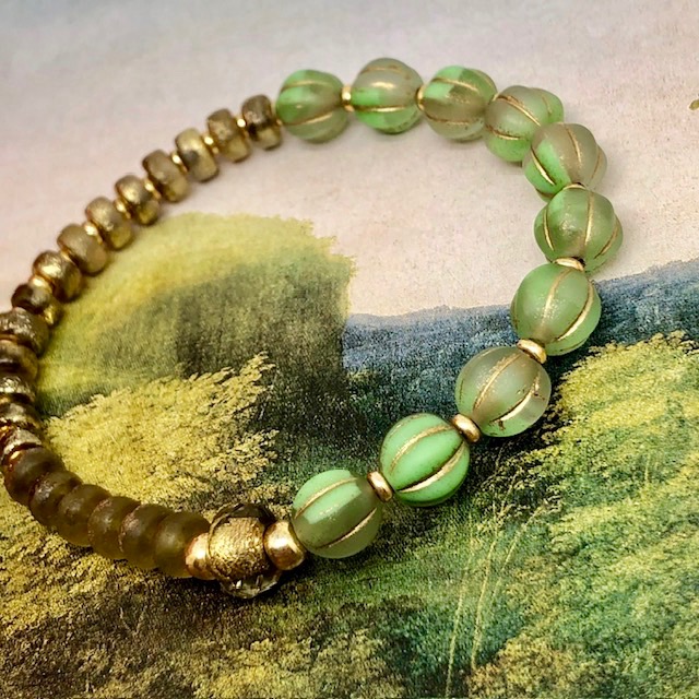 Bracelet élastique asymétrique bohème chic composé de perles en verre de Bohême vert pomme et bronze or. Bracelet stretch de créateur.