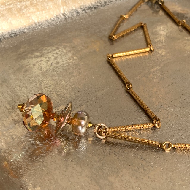 Collier composé d’une belle perle facettée en cristal Swarovski et de perles Lampwork. Chaîne en métal doré. Pièce unique.
