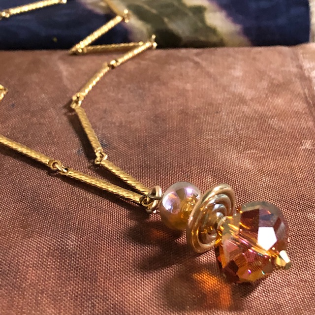 Collier composé d’une belle perle facettée en cristal Swarovski et de perles Lampwork. Chaîne en métal doré. Pièce unique.