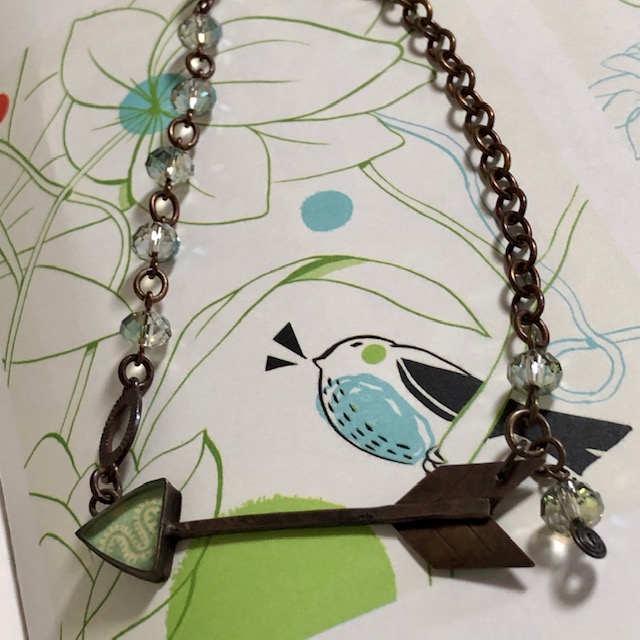 Collier (ras-du-cou) composé d’un pendentif artisanal en résine, de perles en verre tchèque vert pâle et d'un connecteur en métal cuivré. Pièce unique.