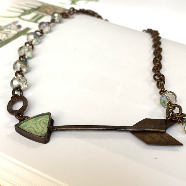 Collier (ras-du-cou) composé d’un pendentif artisanal en résine, de perles en verre tchèque vert pâle et d'un connecteur en métal cuivré. Pièce unique.
