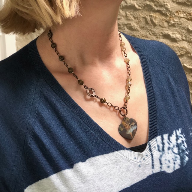 Collier composé d'un pendentif artisanal en cuivre émaillé, d'un connecteur en bronze et de perles en verre tchèque. Chaîne en laiton. Pièce unique.