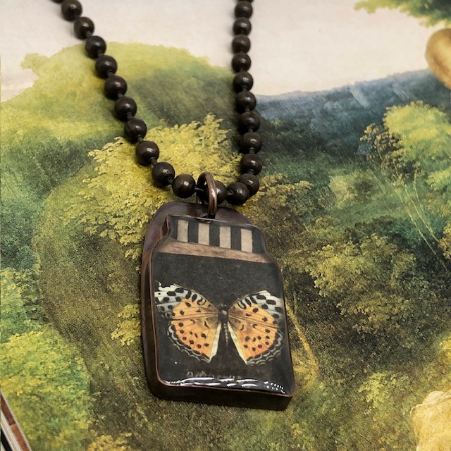 Collier ras-de-cou composé d’un pendentif artisanal en résine et laiton représentant un papillon sous forme de spécimen. Chaîne en laiton. Modèle unique.