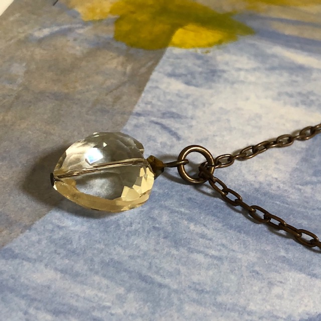 Collier composé d’un coeur facetté en cristal couleur citrine et d’une perle en cristal Swarovski chocolat. Chaîne en laiton.