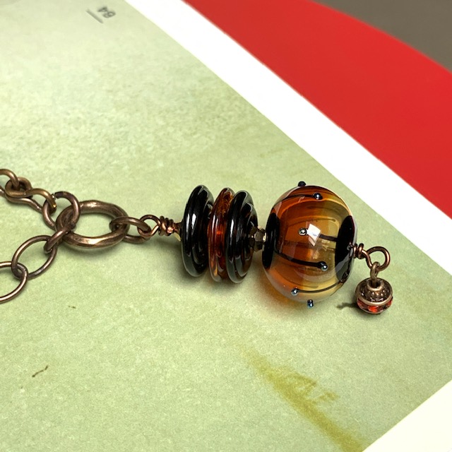 Sautoir asymétrique composé de différentes perles Lampwork ambre et noir. Chaînes et anneaux en laiton. Pièce unique.