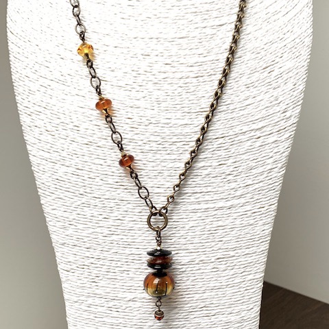 Sautoir asymétrique composé de différentes perles Lampwork ambre et noir. Chaînes et anneaux en laiton. Pièce unique.